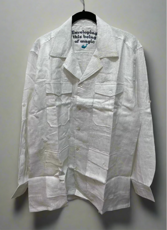 White safari shirt on a hanger against a beige wall